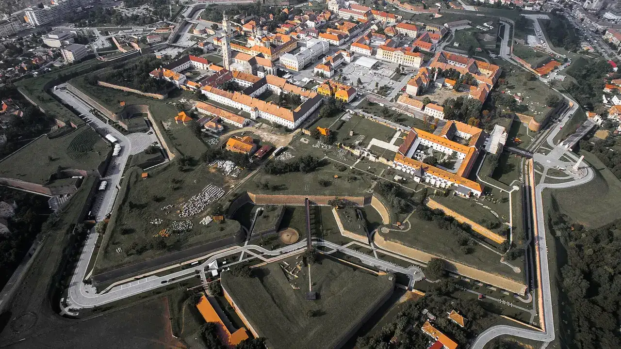Aerial view of the Alba Carolina citadel in Alba Iulia, its grassy seven-pointed star of bastions and ditches wrapped around the old town of red-roofed houses and church towers