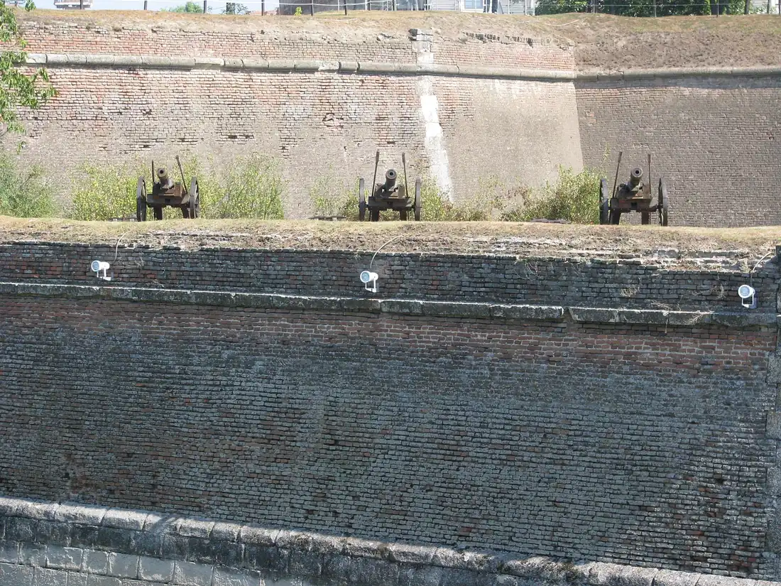 Old iron cannons on the grass terrace between the upper and lower brick walls of the Alba Carolina fortification