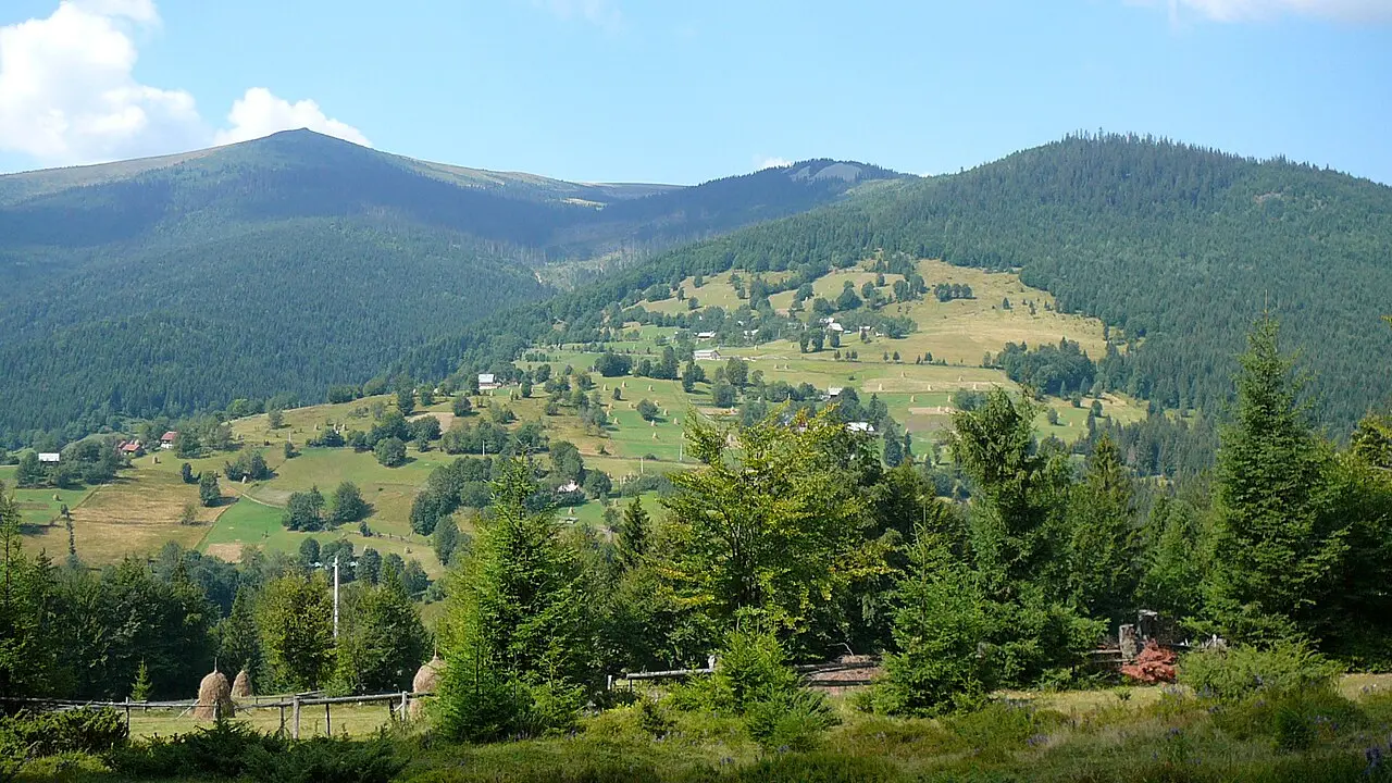 Wooden rural buildings and green hills around the village of Arieseni in the Apuseni Mountains