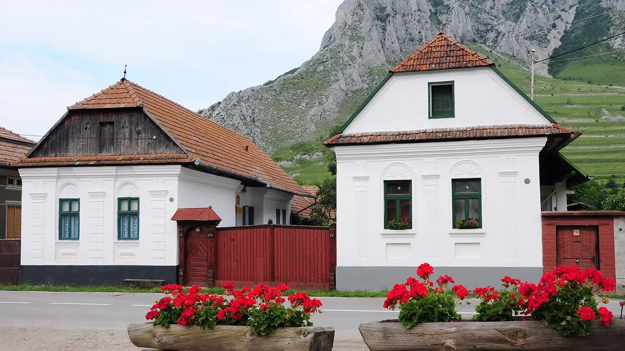 Whitewashed houses with red tile roofs in the stone village of Rimetea below a limestone cliff