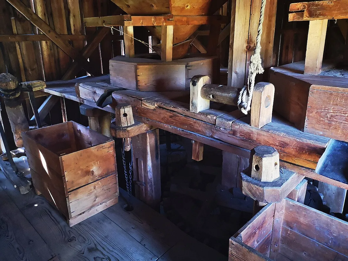 The wooden grinding mechanism and grain hopper inside a working mill building at ASTRA Museum