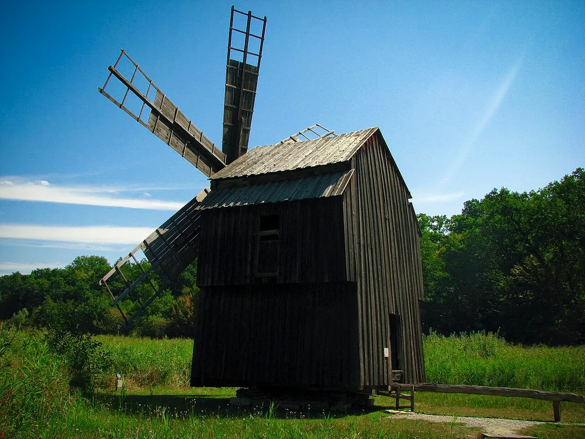 A wooden windmill at ASTRA Museum with bare wooden lattice sails, its whole body pivoted to face the wind