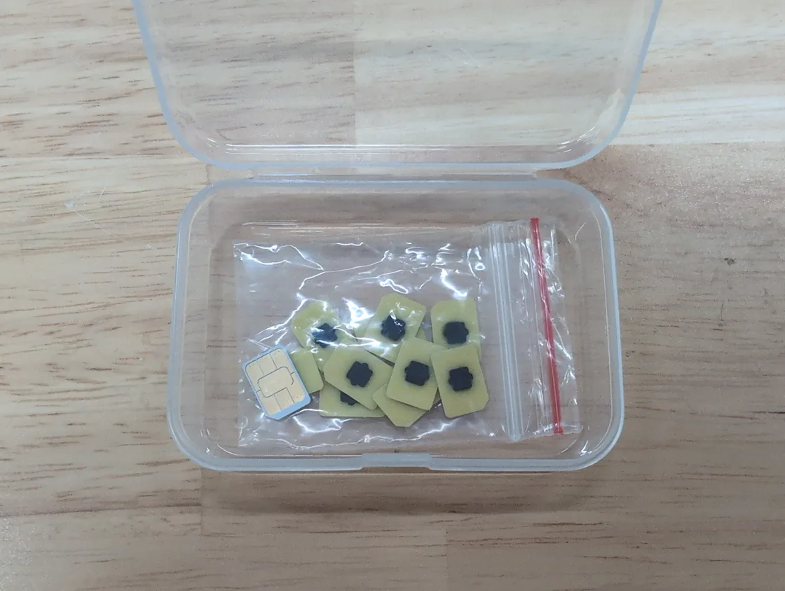 A row of tiny eUICC (eSIM) chips next to a nano-SIM card in a small case, the embedded chip that replaces a physical SIM in modern phones