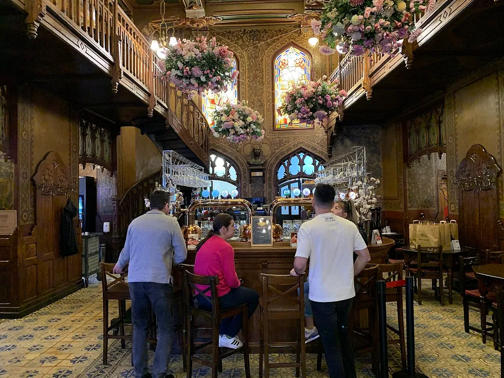The Gothic-Revival main hall of Caru cu Bere in Bucharest, carved wood, painted vaults and stained glass above the tables