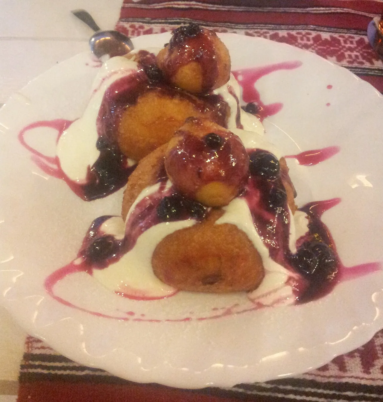 A plate of papanasi, Romanian fried sweet-cheese doughnuts topped with sour cream and berry jam