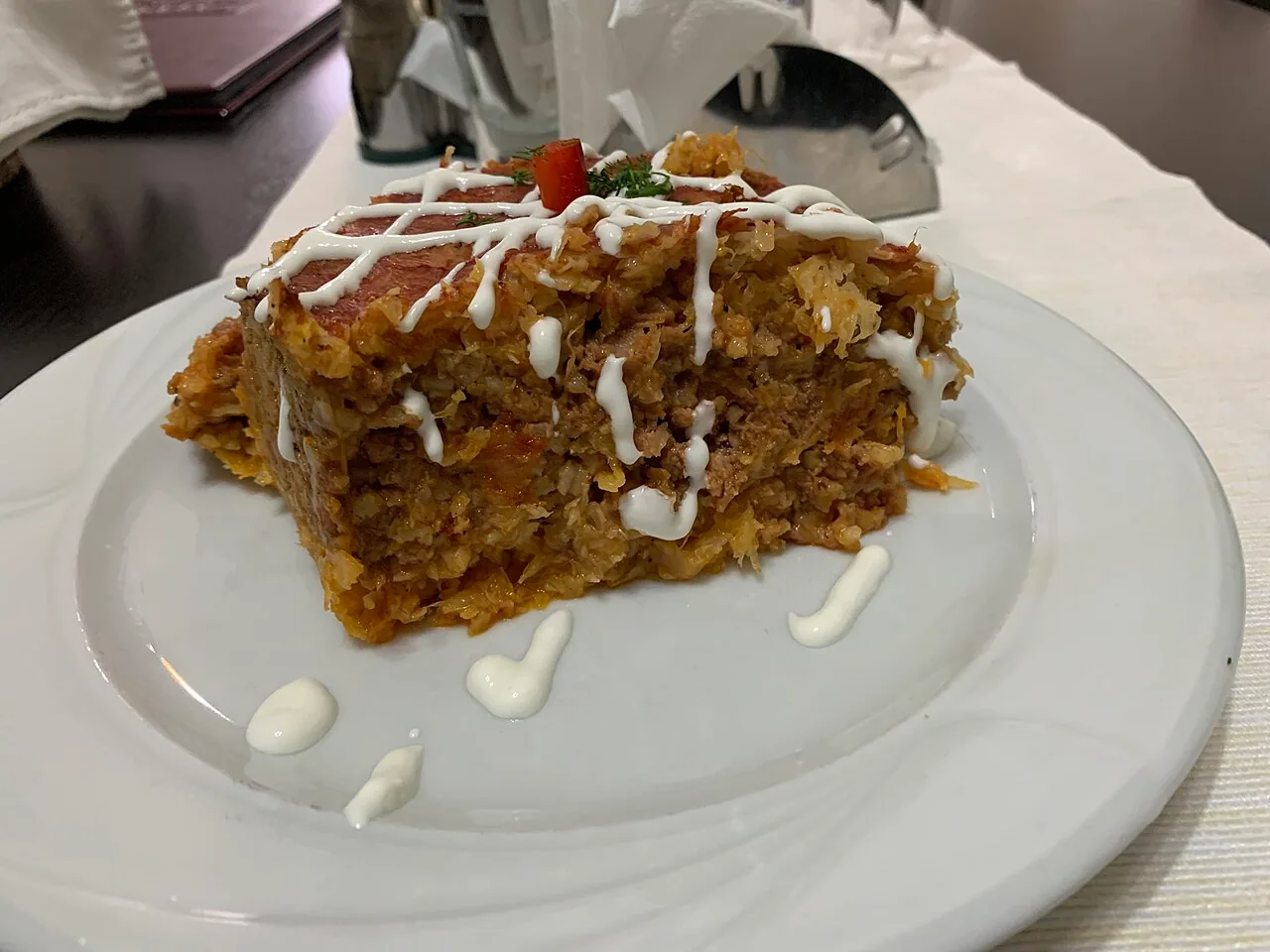 A serving of varza a la Cluj, the layered cabbage, minced meat and rice bake topped with sour cream