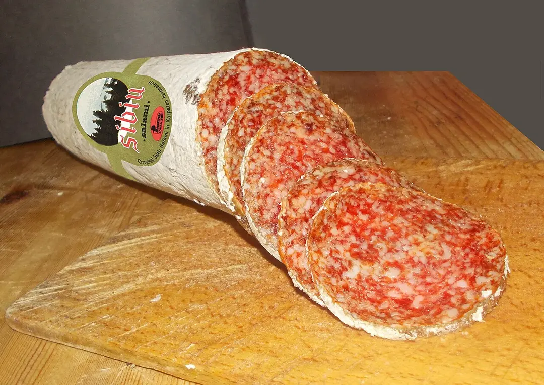 Sliced Salam de Sibiu, the dry-cured salami with a white mould rind, on a board