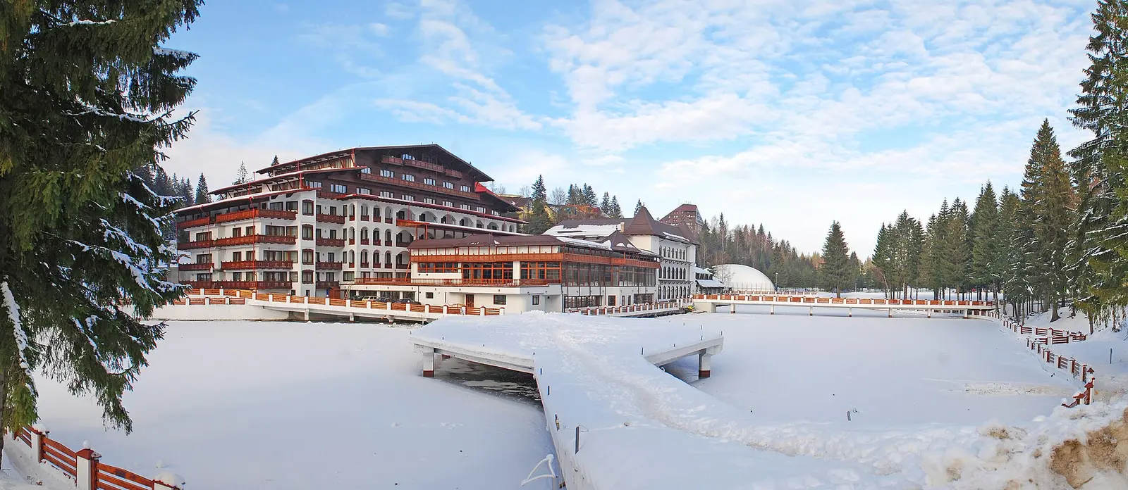 A panorama of Poiana Brasov ski resort under snow, hotels and pistes below the forested slopes of Postavaru, Romania's main winter sports base