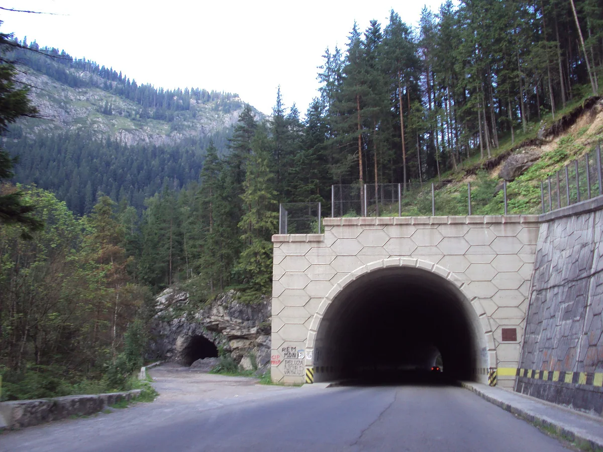 The stone-faced portal of the Lacu Rosu road tunnel on DN12C, with the smaller original tunnel bore visible to the left of it