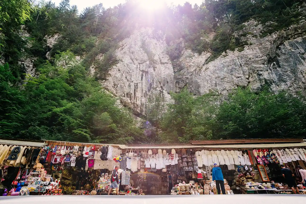 A long line of souvenir stalls hung with woollen goods and wooden crafts at the foot of a huge limestone wall in the Bicaz Gorge