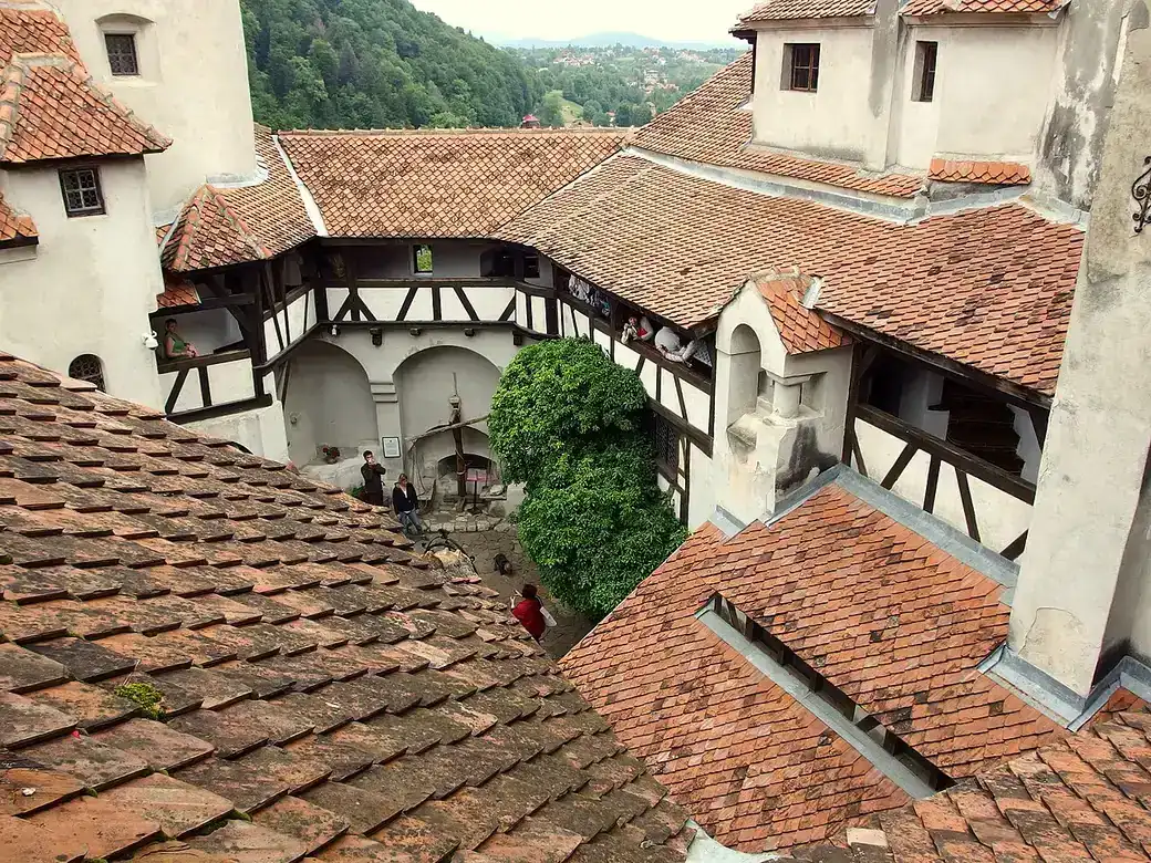 View over the tiled roofs of Bran Castle toward the Bran valley and hills beyond