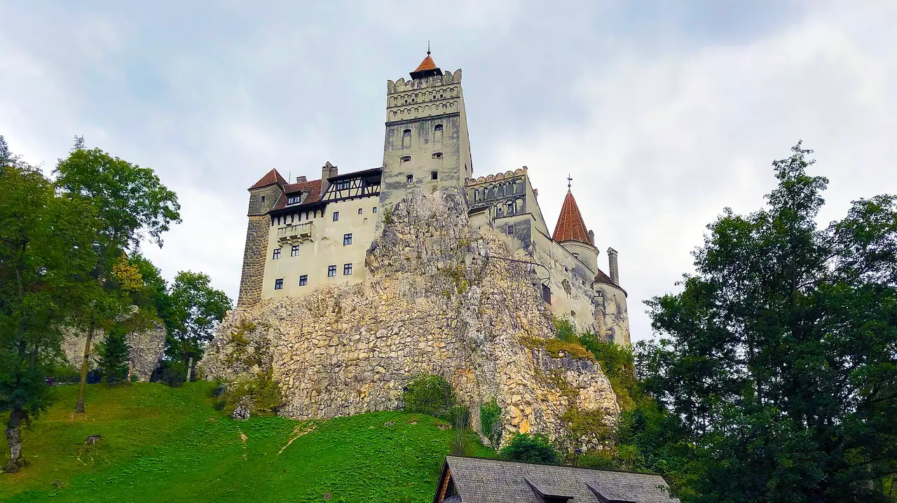 Bran Castle standing on its rocky crag above the village of Bran, seen from the lawn below