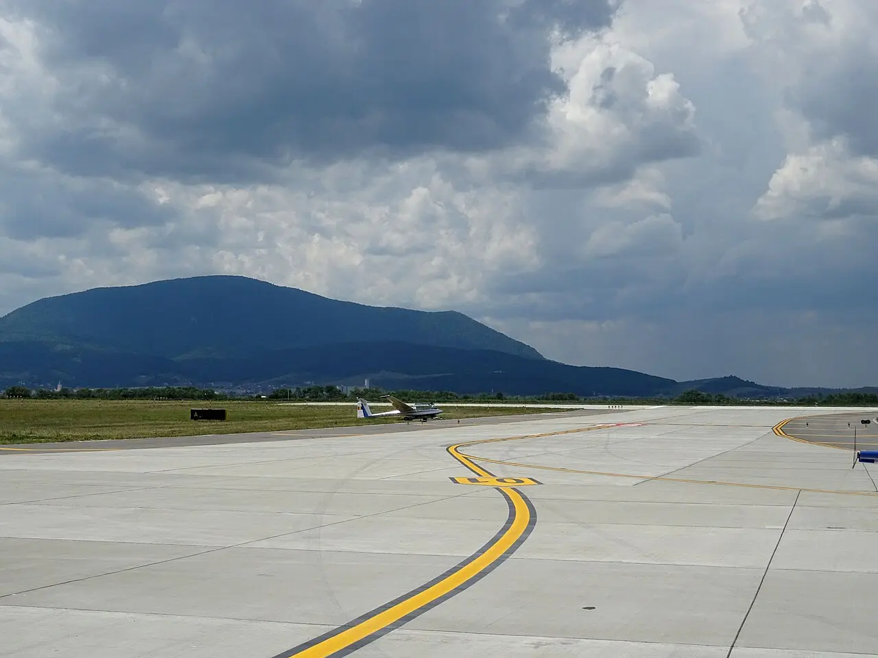 Aircraft and ground equipment on the apron at Brasov-Ghimbav Airport under a clear Transylvanian sky