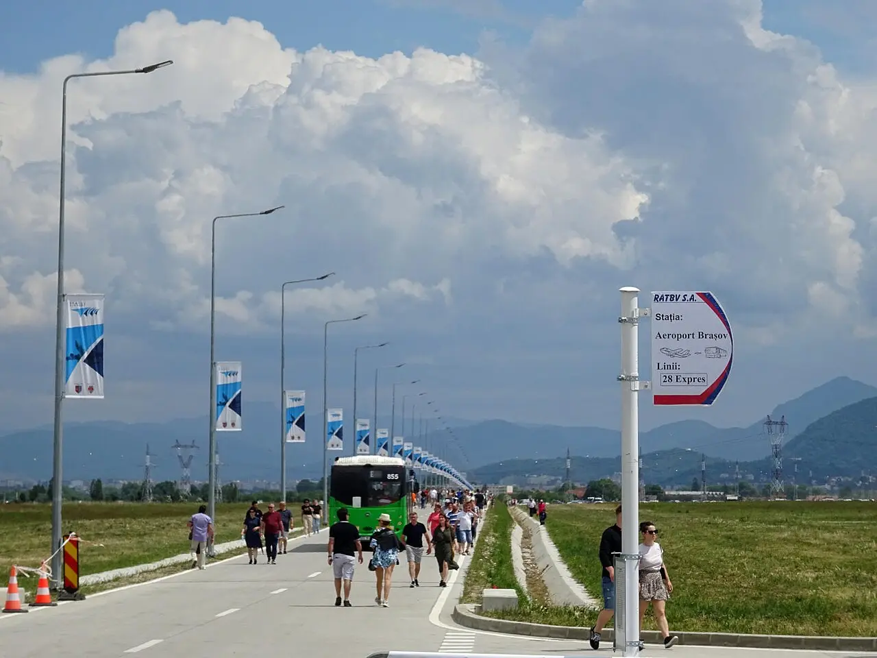 RATBV stop pole outside the Brasov-Ghimbav terminal with its printed route board, a city bus waiting further back