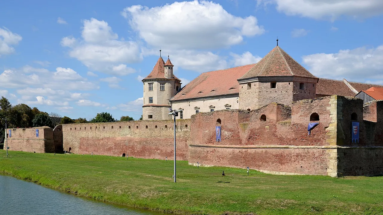 The brick walls, red-tiled towers and moat of Fagaras citadel, the halfway fortress on the Brasov to Sibiu road
