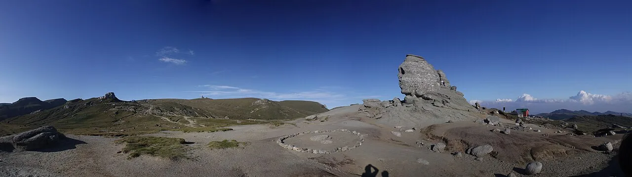 The Bucegi Sphinx rock formation in profile, its nose and brow carved by erosion against a bright sky