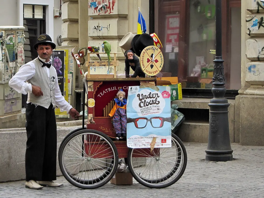 A costumed street performer with a fortune-telling barrel organ cart on a cobbled Lipscani street in Bucharest