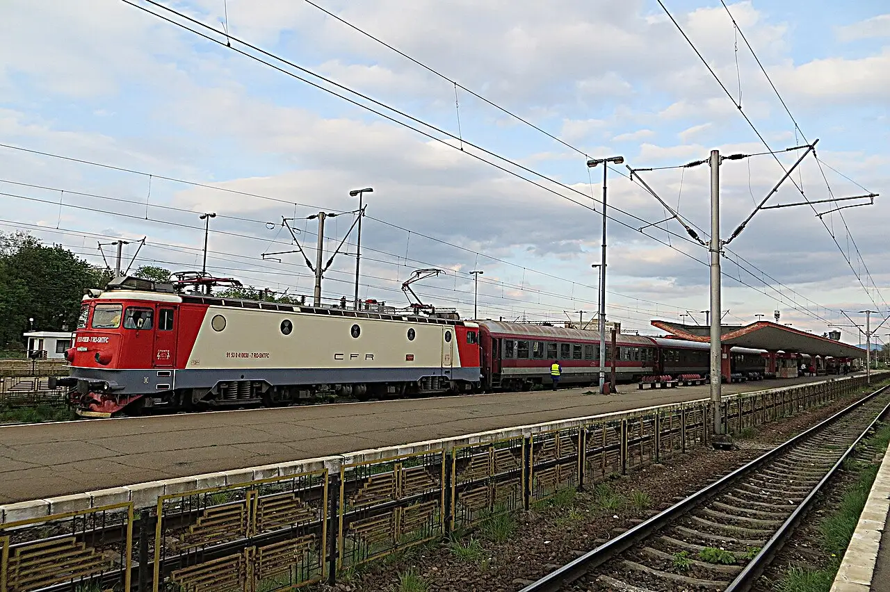 A CFR train with red carriages standing at the platform in Brasov station at dusk, the end of the line from Bucharest