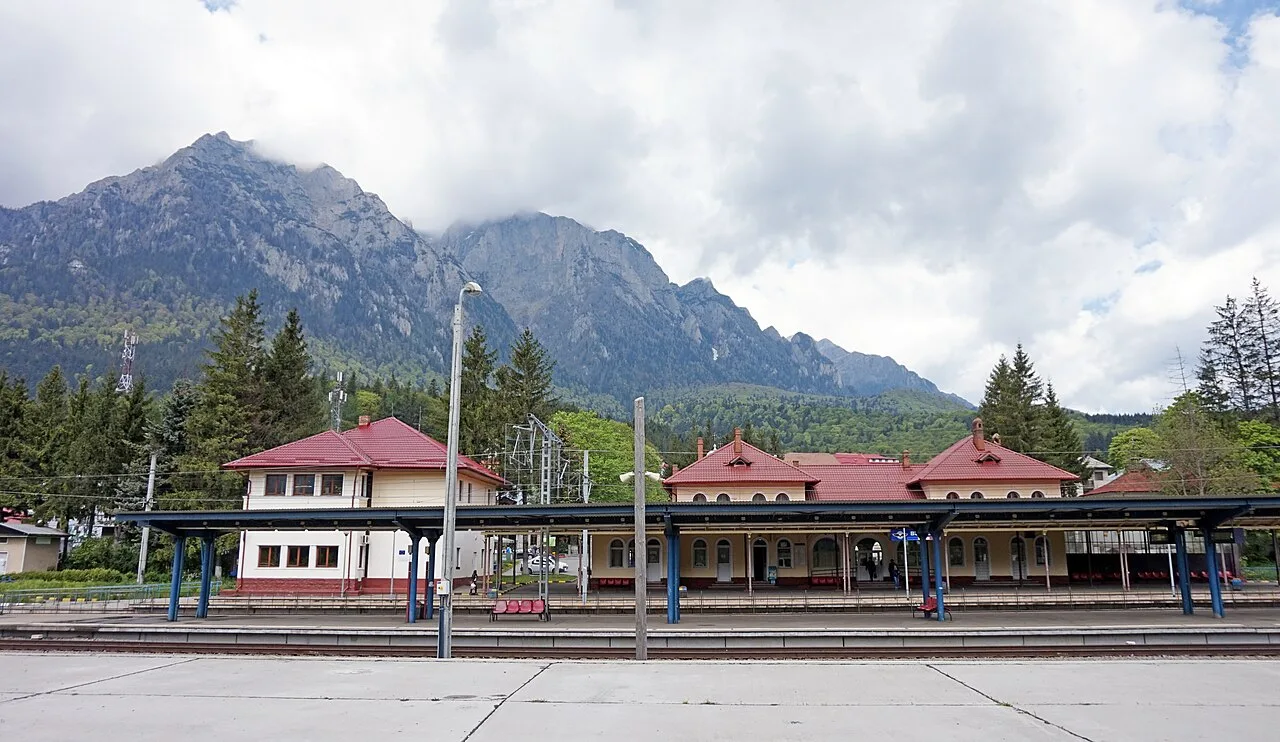 The platform at Busteni station on the Bucharest to Brasov line with the sheer grey wall of the Bucegi mountains rising directly behind it