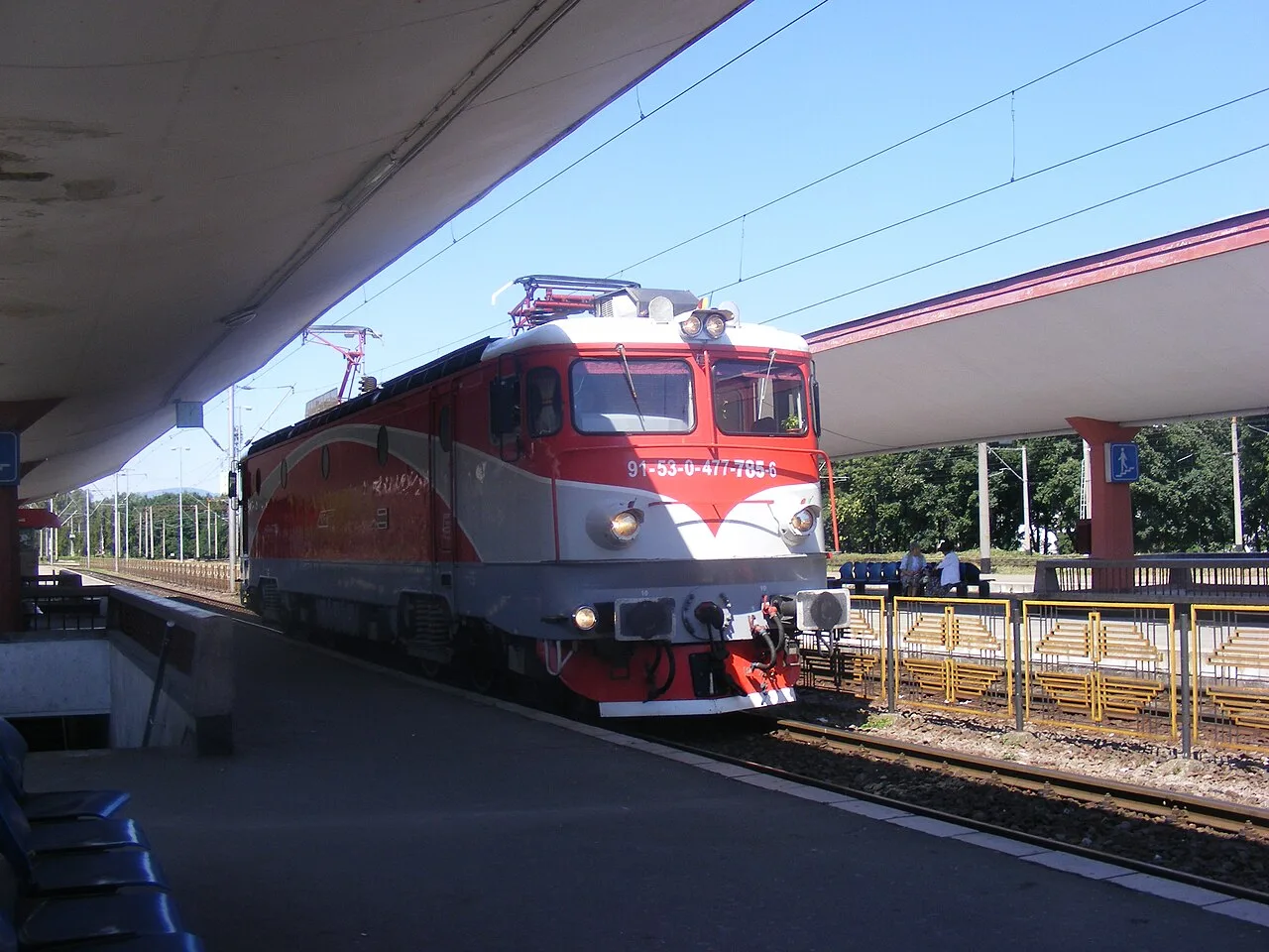 A red and white CFR electric locomotive waiting at a platform at Brasov railway station, the train most travellers take from Bucharest