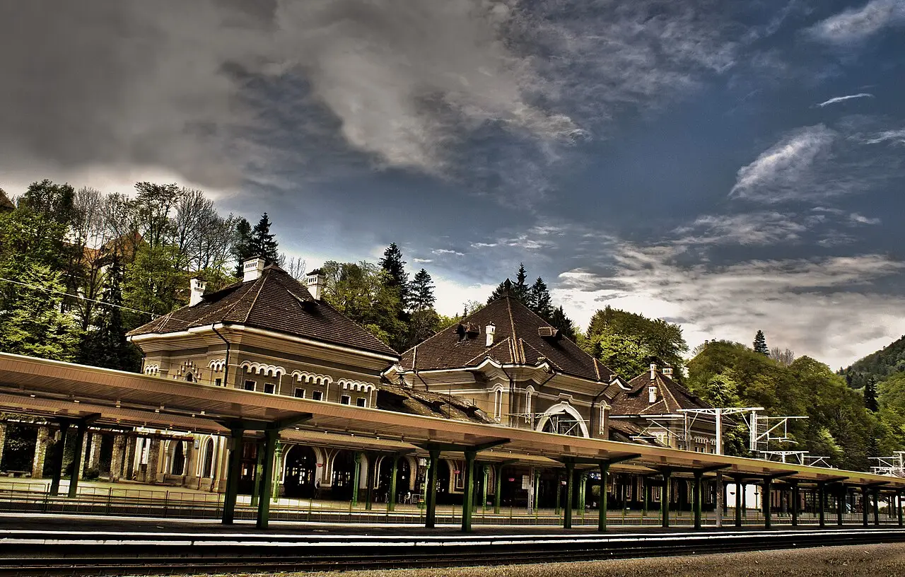The ornate historic railway station building at Sinaia under a dramatic sky, one of the stops on the Bucharest to Brasov line