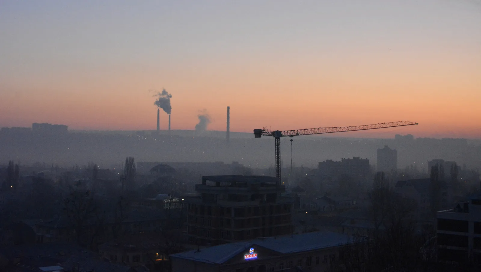 Chisinau at first light, low-rise apartment blocks and green tree cover spreading out under a soft morning sky - the view that greets travellers off the night train