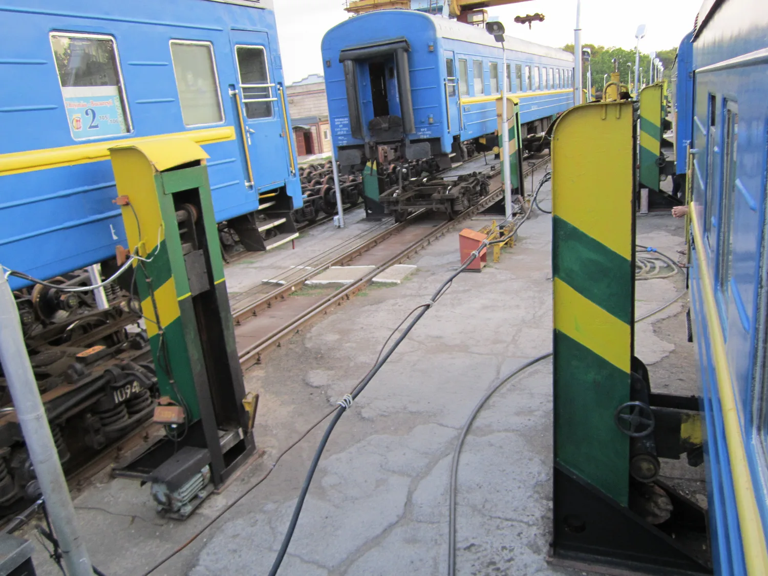 A railway carriage raised on heavy jacks inside a shed at Ungheni, its wheel bogie removed underneath, during the gauge change on the Moldovan border