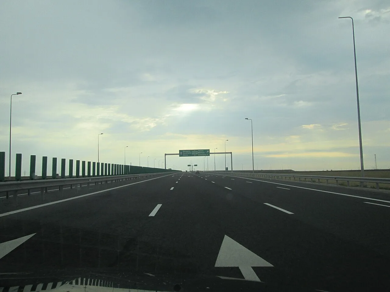 The A2 motorway approaching Constanta with overhead gantry signs for Constanta, Mamaia and the southern resorts under a cloudy sky