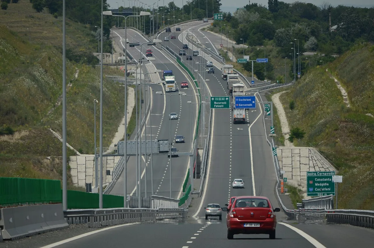 The A2 Sun Motorway from Bucharest with green road signs to Constanta and Cernavoda and a red car in the near lane