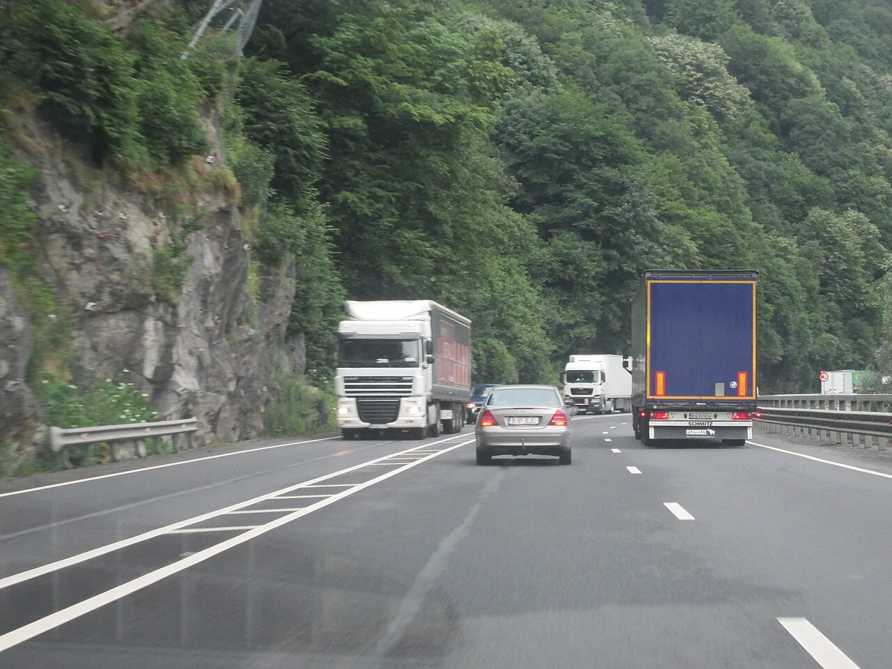 The DN7 national road running as a 2+1 carriageway through the wooded Olt Valley between rocky slopes, the direct road route from Bucharest to Sibiu