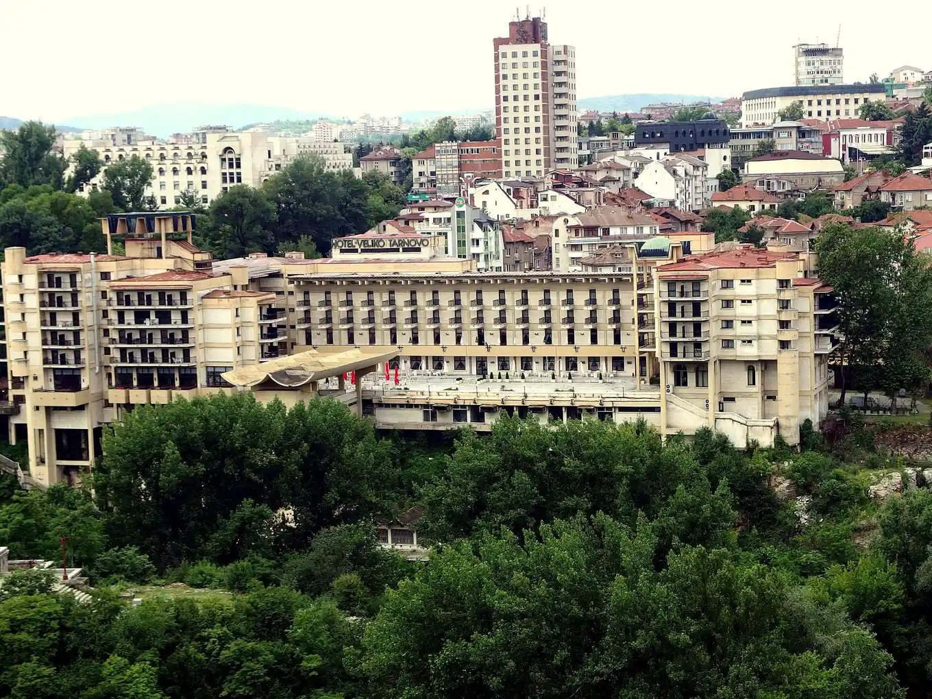 Veliko Tarnovo climbing its hillside, tiled roofs and apartment blocks stacked up the slope with the Hotel Veliko Tarnovo sign visible