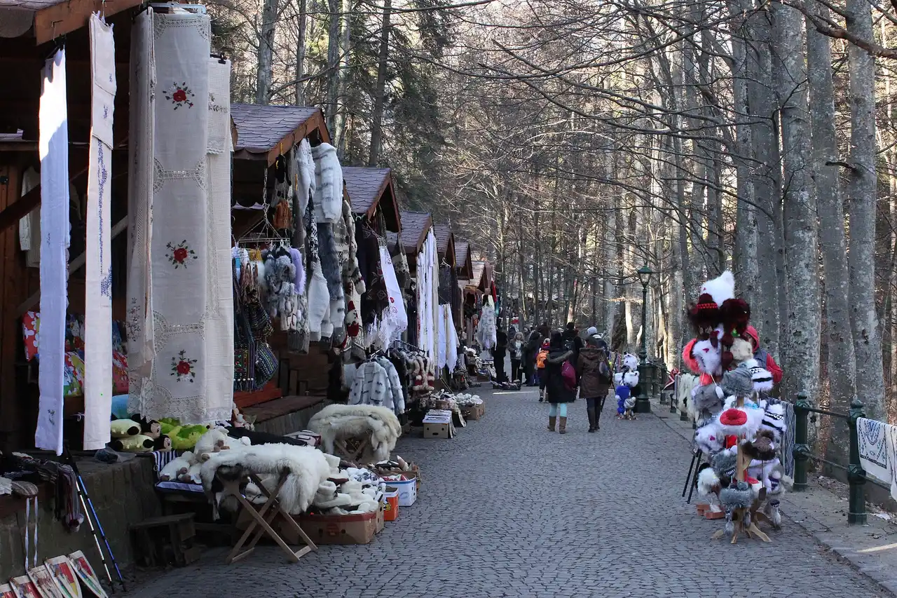 Craft stalls selling embroidered linens and fur hats along the cobbled path up to Peles Castle in Sinaia