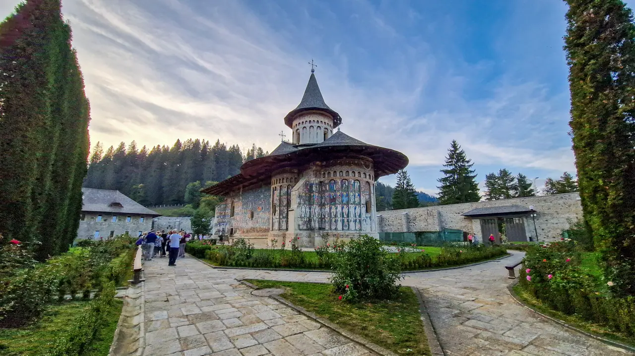 Voronet Monastery church with its blue-painted apse and shingled tower, seen from the courtyard