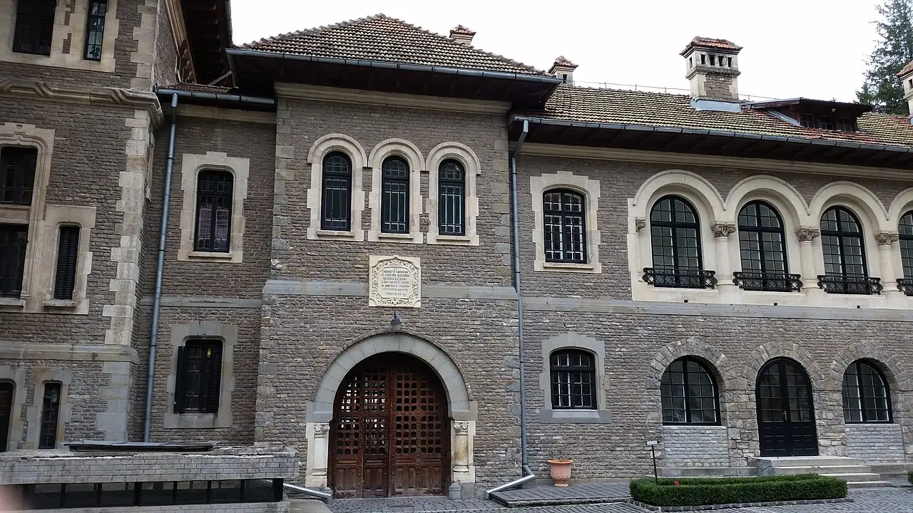 The facade of Cantacuzino Castle, showing an arched carved-stone doorway, twin arched windows above and a row of columned arcade windows to the right