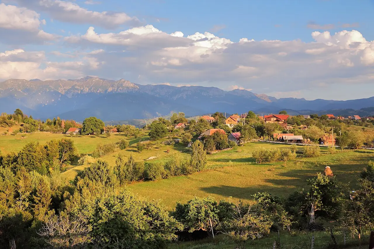 The long limestone ridge of Piatra Craiului seen from Magura village, a pale saw-toothed crest rising above green forested foothills
