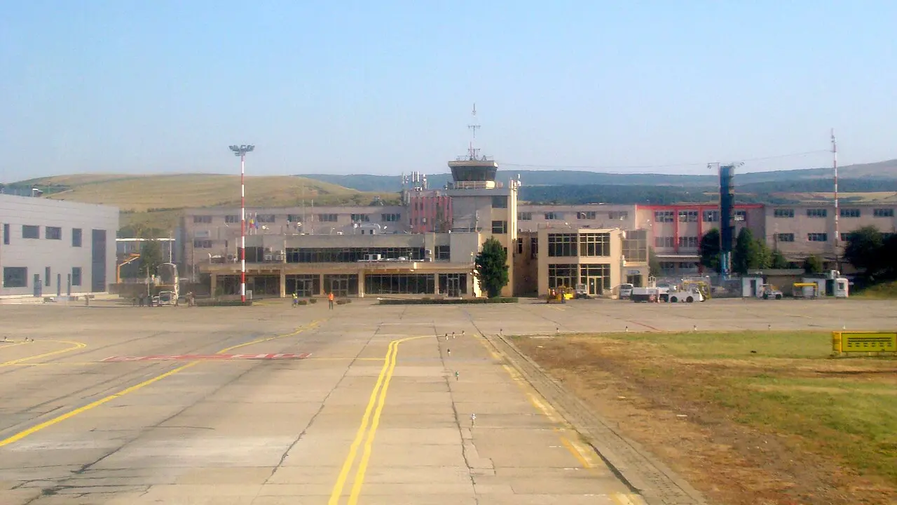 Cluj-Napoca International Airport terminal and apron under a clear sky, with aircraft and airport buildings east of the city