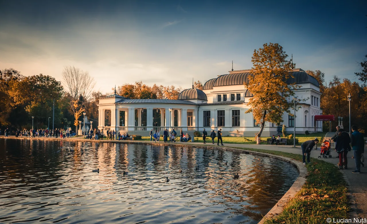 The white neoclassical Casino building in Cluj-Napoca Central Park reflected in the boating lake at golden hour
