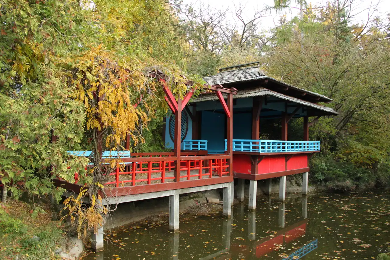 The red-and-blue Japanese tea pavilion standing on stilts over a pond in the Cluj-Napoca Botanical Garden in autumn
