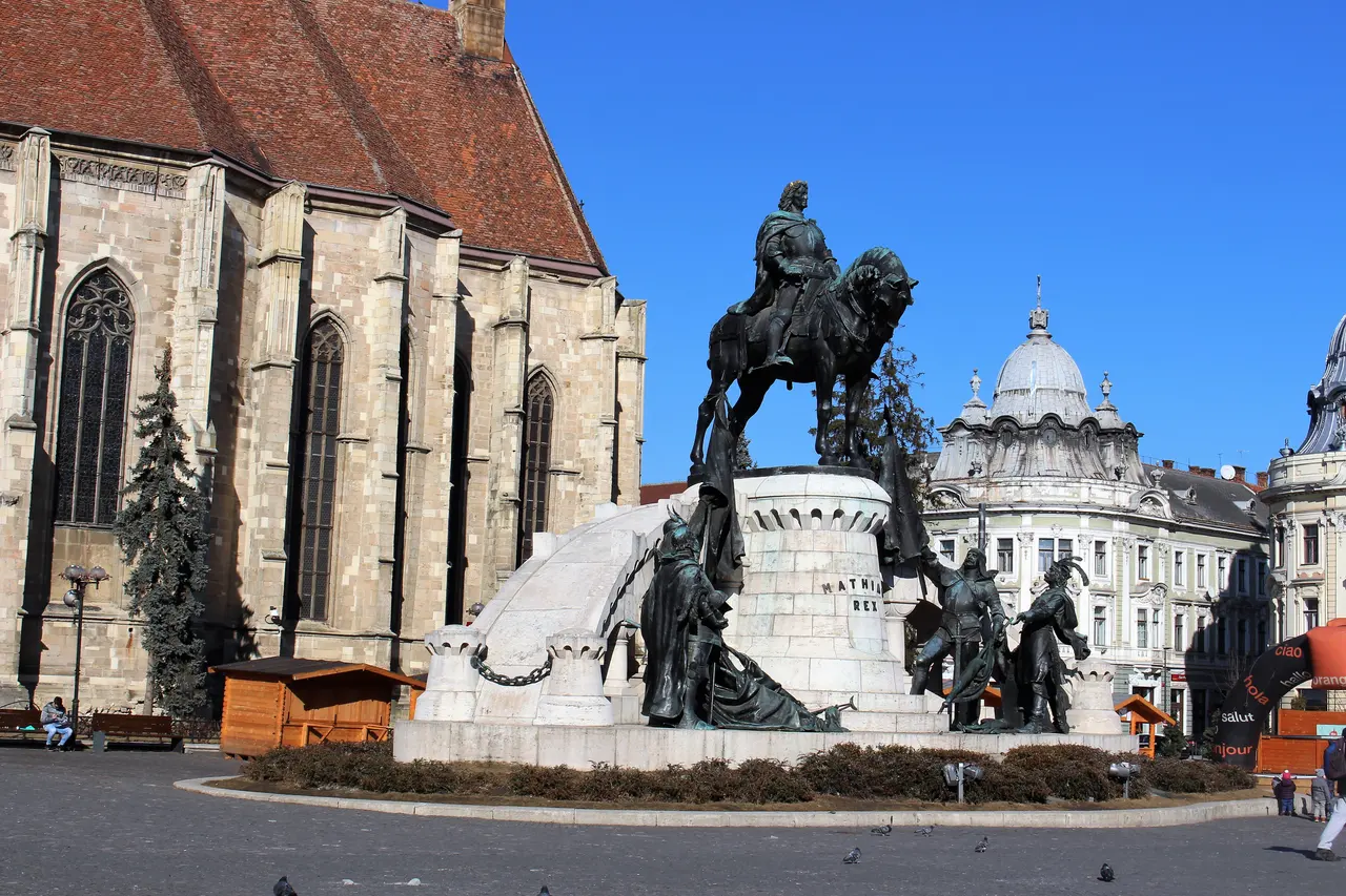 The bronze equestrian statue of Matthias Corvinus and his four generals on Union Square in Cluj-Napoca, with the Gothic church behind