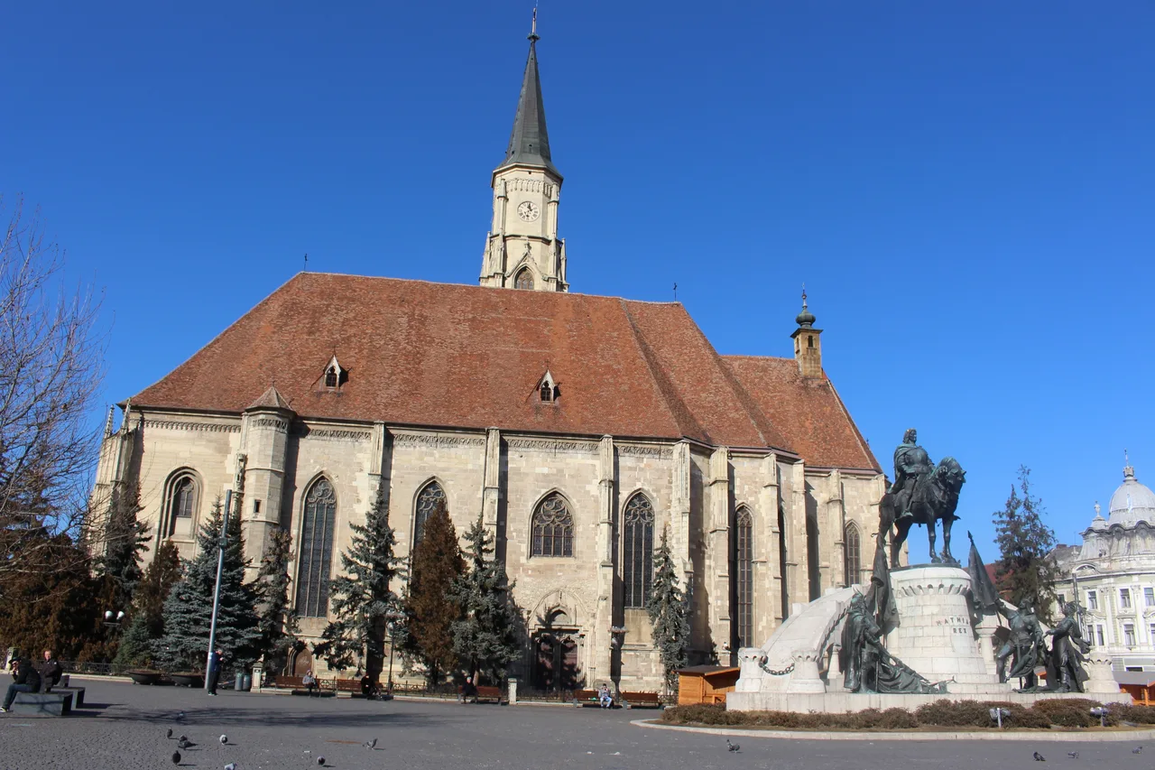 St Michael's Church in Cluj-Napoca, a large Gothic church with a tall 19th-century spire, seen across Union Square