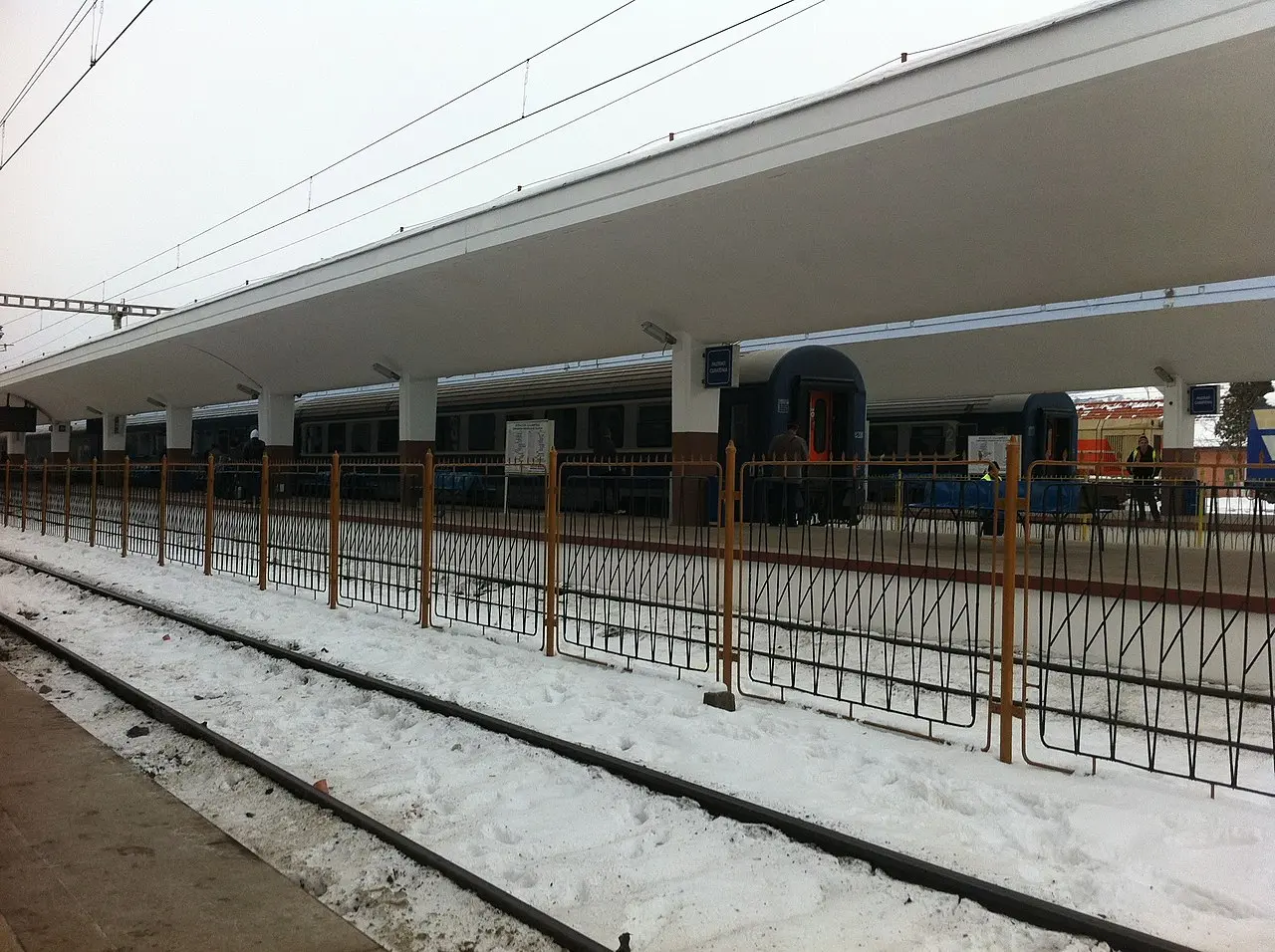 Platforms at Cluj-Napoca railway station with passengers waiting beside a long train
