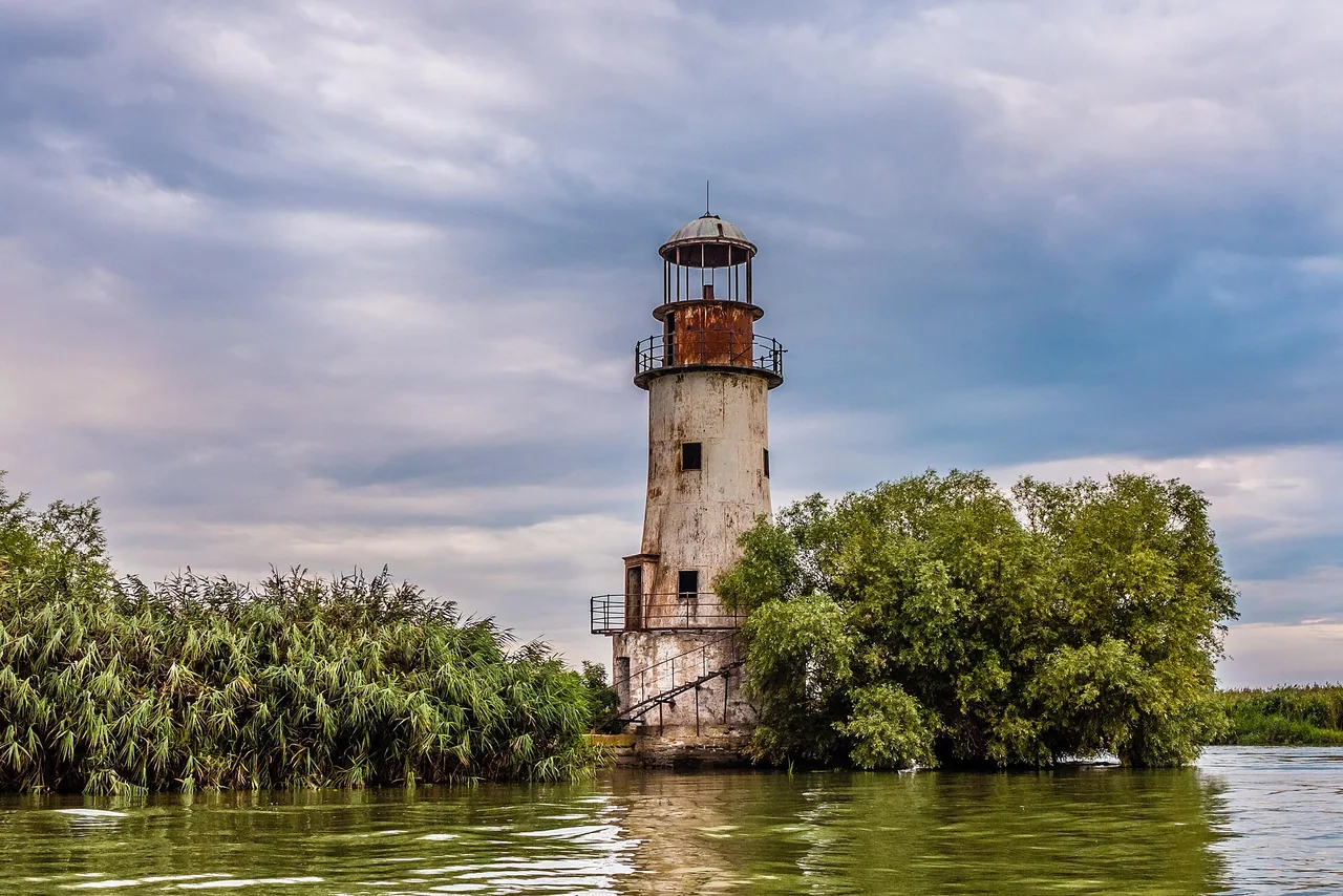 The weathered old lighthouse of Sulina rising above reeds and water in the Danube Delta