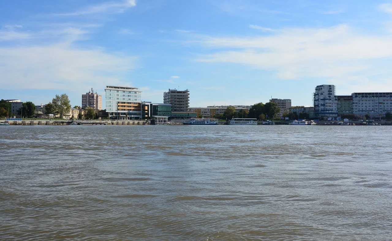 The Tulcea waterfront on the Danube, a working port with moored boats and low hills behind