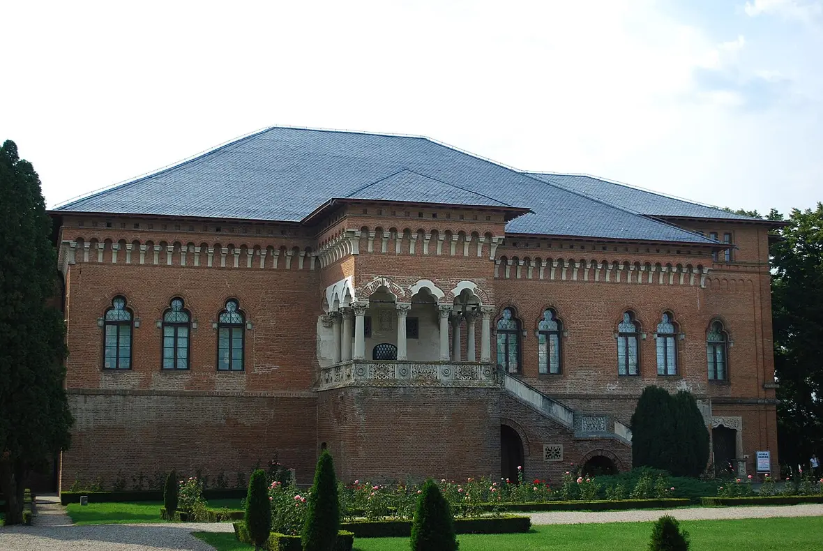 The brick facade and carved stone loggia of Mogosoaia Palace, with clipped hedges and a rose garden in front