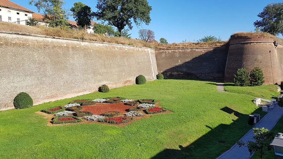 Brick bastion of the Alba Carolina citadel above a lawn with a star-shaped flowerbed, Alba Iulia