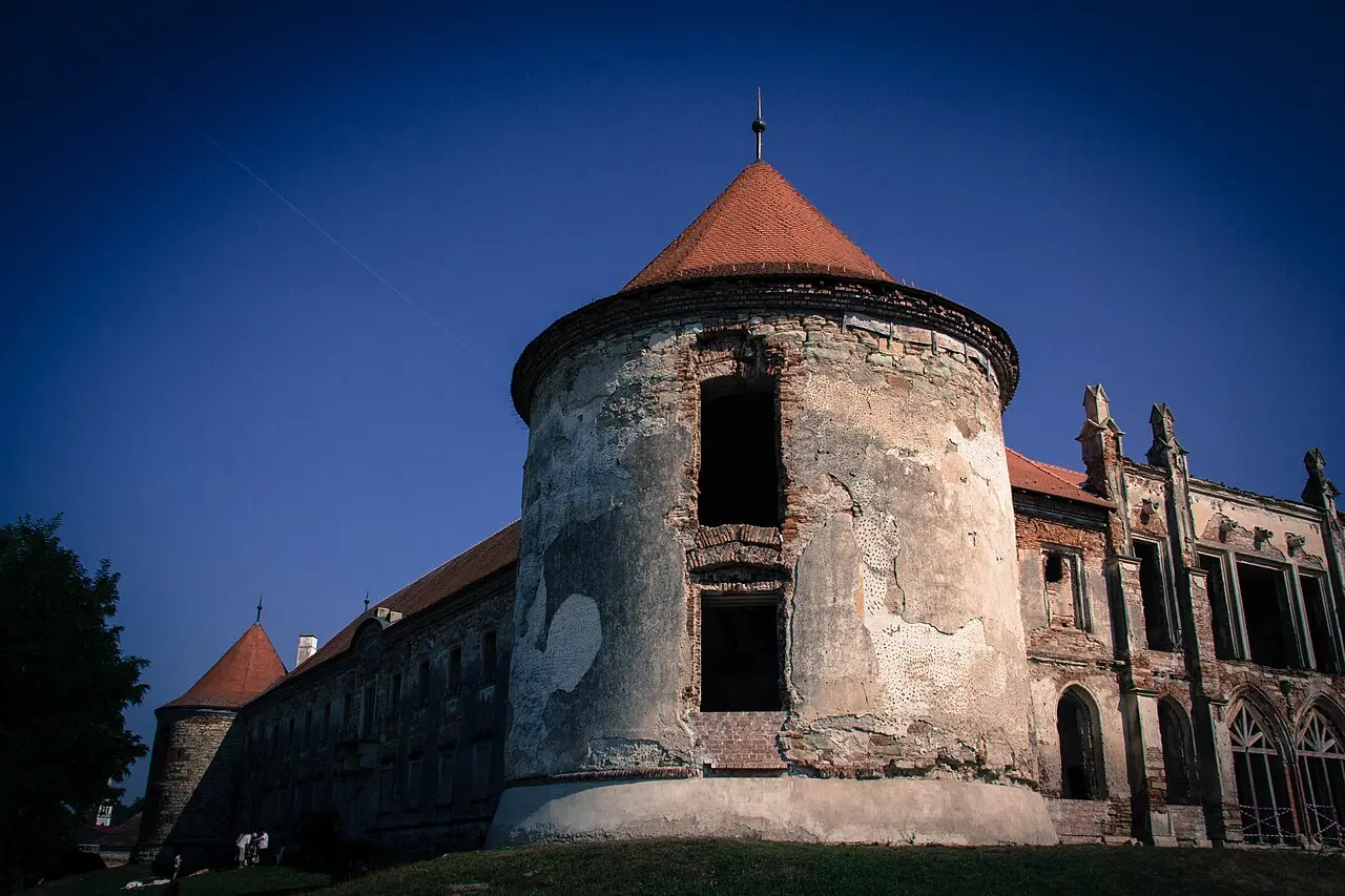 Weathered towers and orange conical roofs of Banffy Castle at Bontida under a clear blue sky