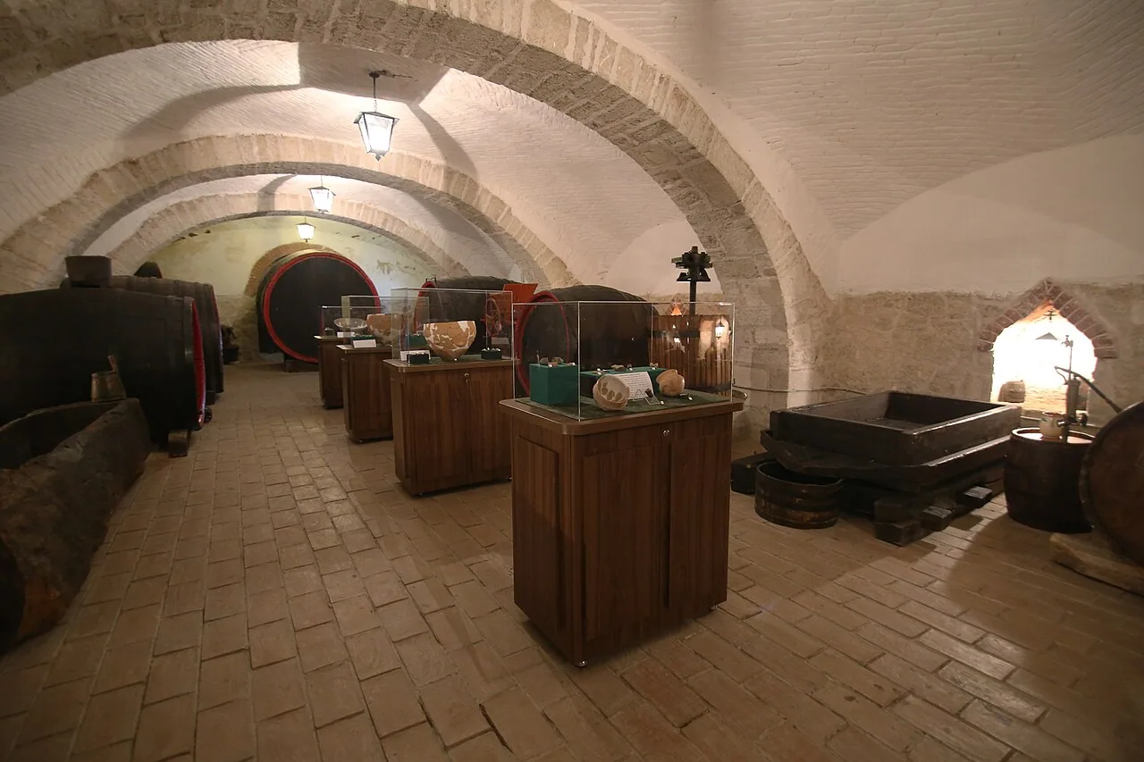 The vaulted cellar inside Conacul Bellu in Urlati, now a museum room lined with old wine barrels and display cases