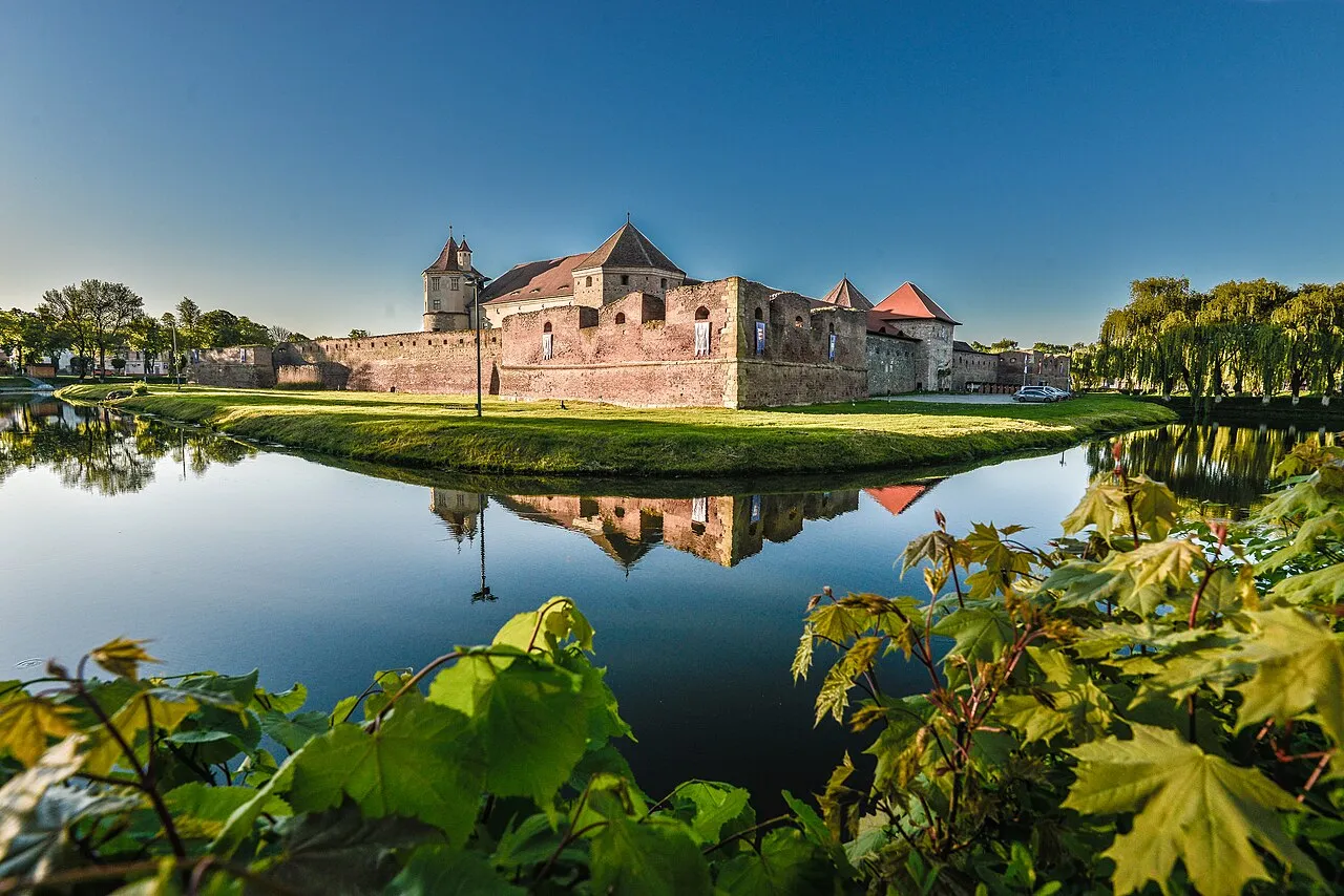 Fagaras citadel in summer sun, brick bastions and towers rising above the town roofs