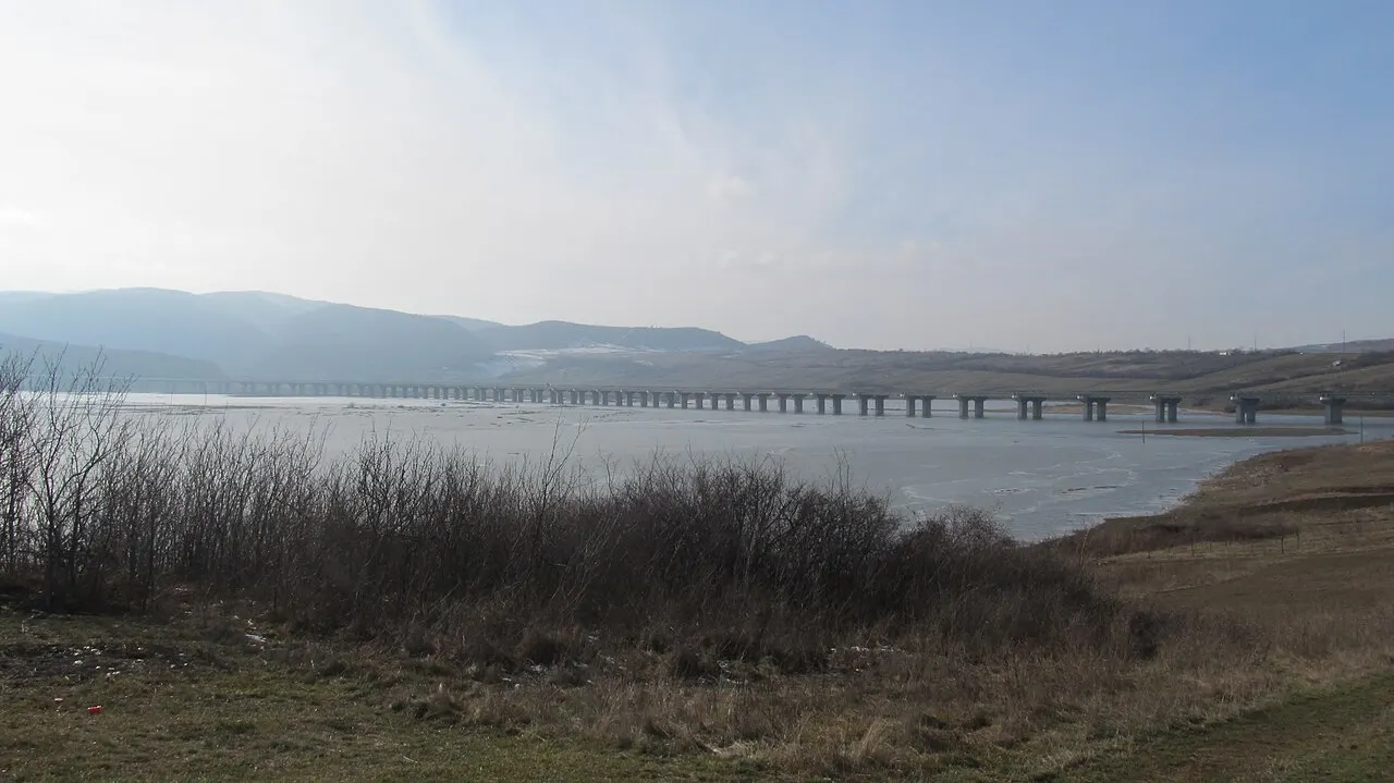 A viaduct on the A3 motorway in Romania curving across a green valley, empty carriageways under a bright sky
