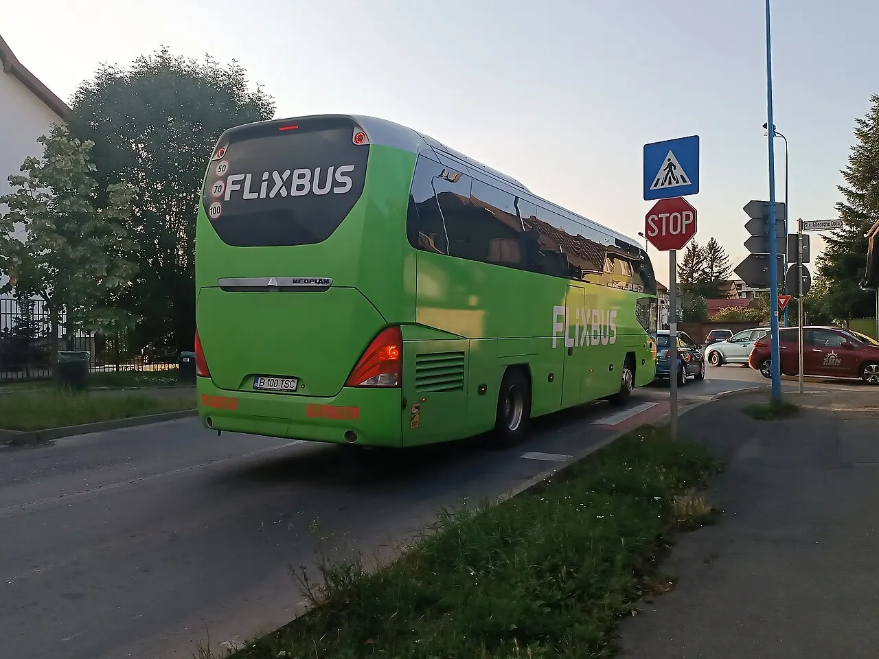 A green FlixBus intercity coach parked at a stop in Brasov, Romania, with passengers and luggage alongside